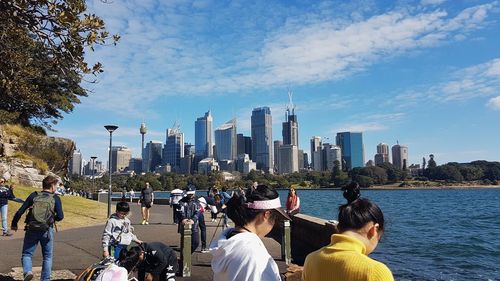 People at modern buildings in city against sky