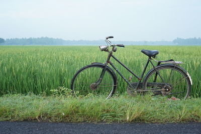 Bicycle parked on field against sky