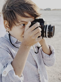 Close up portrait of a child taking a photo with a vintage camera