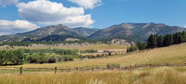 Scenic view of field by mountains against sky