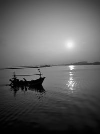 Silhouette man in sea against sky during sunset