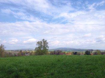 Scenic view of grassy field against cloudy sky