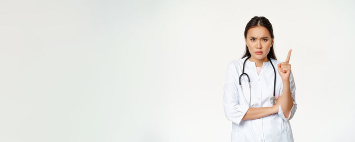 Portrait of young woman standing against white background