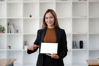 Portrait of businesswoman showing digital tablet