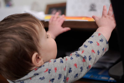 A baby is reaching for objects laid out on dad's table