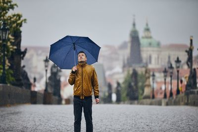 Man standing on wet umbrella in city during rainy season