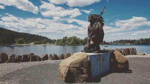 Statue of harbor by river against sky