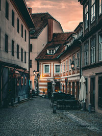 Street amidst buildings against sky during sunset