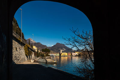 Scenic view of river by mountains against clear blue sky