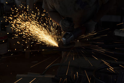 Sparks from steel. metal sawing. lights in dark. work in garage. sawing workpiece.