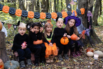 Happy kids in halloween costumes having fun in halloween decorations outdoor