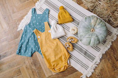 Directly above shot of baby warm clothes with pumpkins on hardwood floor