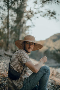 Portrait of man wearing hat sitting on land