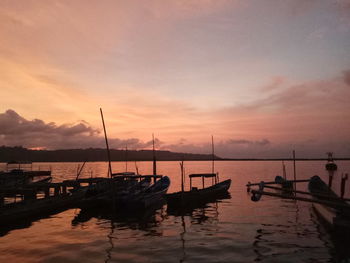 Sailboats moored in marina at sunset