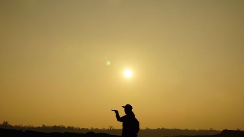 Silhouette woman gesturing against sky during sunset