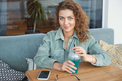 Portrait of smiling young woman with drink at cafe