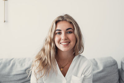 Portrait of young woman standing against white background
