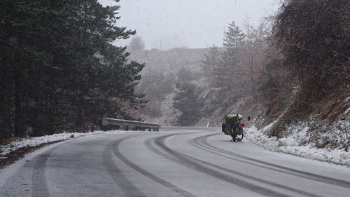 Rear view of person riding bicycle on road during winter