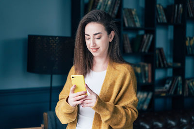 Smiling woman using mobile at home