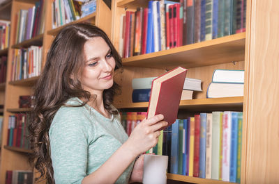 Smiling woman holding book in library