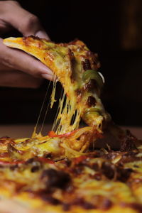 Close-up of hand holding pizza