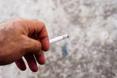 Close-up of hand holding cigarette