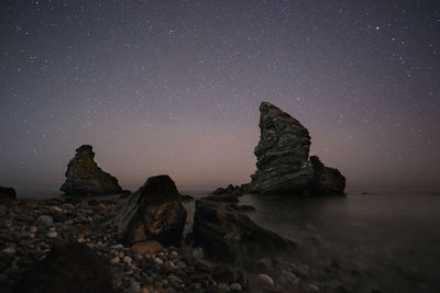 Rock formation in sea against sky at night