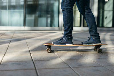 Male in sneakers riding on longboard on paving stones or asphalt. selective focus on skateboard.