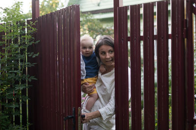 Portrait of young woman standing by fence