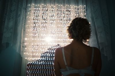 Rear view of woman standing by window