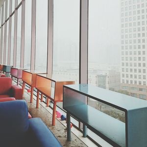 Tables and armchairs on floor in building during foggy weather