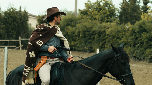 Side view of woman riding horse on field