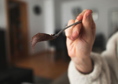 A young woman hand holding spoon filled with chocolate