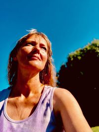 Portrait of smiling woman against blue sky