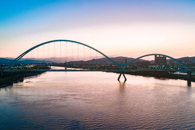 Bridge over river against sky during sunset