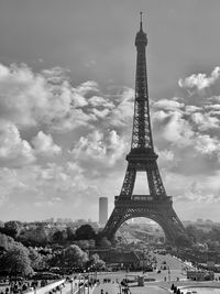 View of communications tower in city against cloudy sky