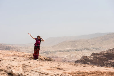 Full length of woman standing on mountain against clear sky