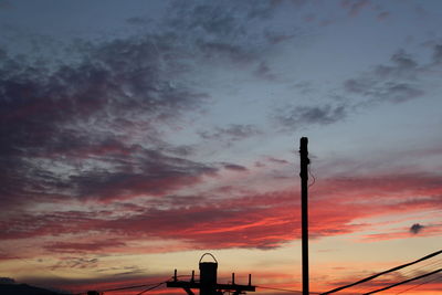 Low angle view of silhouette smoke stack against sky during sunset