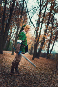 Side view of young man wearing cosplay costume while standing in forest during autumn