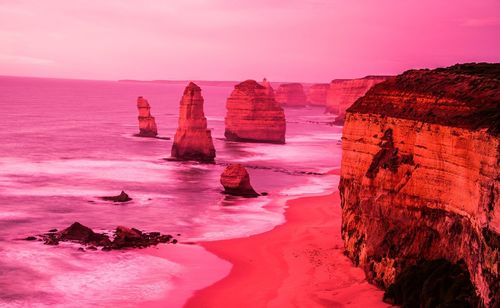 Rock formation on beach against sky during sunset