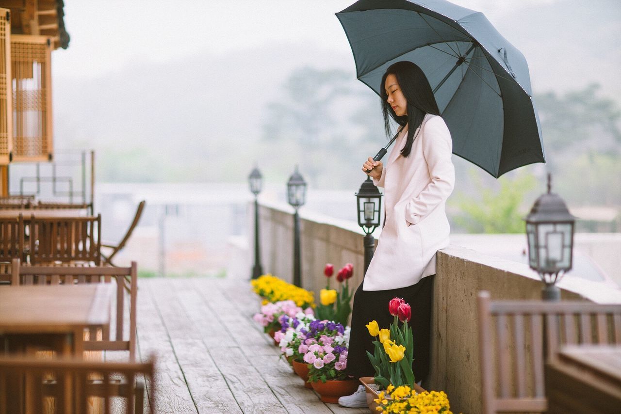 sky, building exterior, built structure, architecture, focus on foreground, railing, lifestyles, cloud - sky, flower, day, leisure activity, casual clothing, freshness, water, outdoors, incidental people, nature, standing