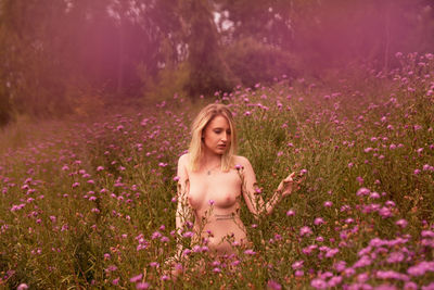 Portrait of woman with purple flowers on field