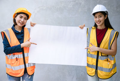 Portrait of a smiling young woman standing against wall