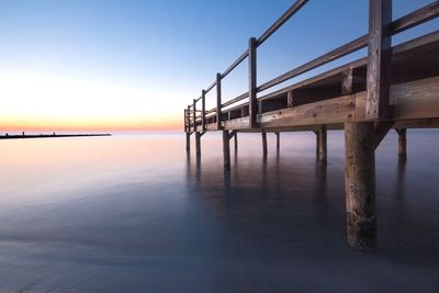 Pier over sea against sky during sunset