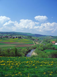 Scenic view of fields against blue sky and clouds