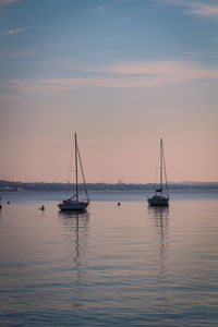 Sailboat sailing on sea against sky during sunset