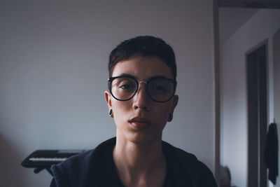 Portrait of young woman wearing sunglasses against wall
