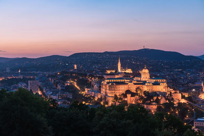 High angle view of city lit up at sunset