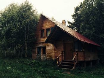 Wooden house on field by trees