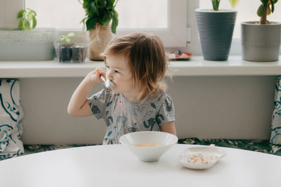 A little girl is sitting at the kitchen table eating soup. high quality photo